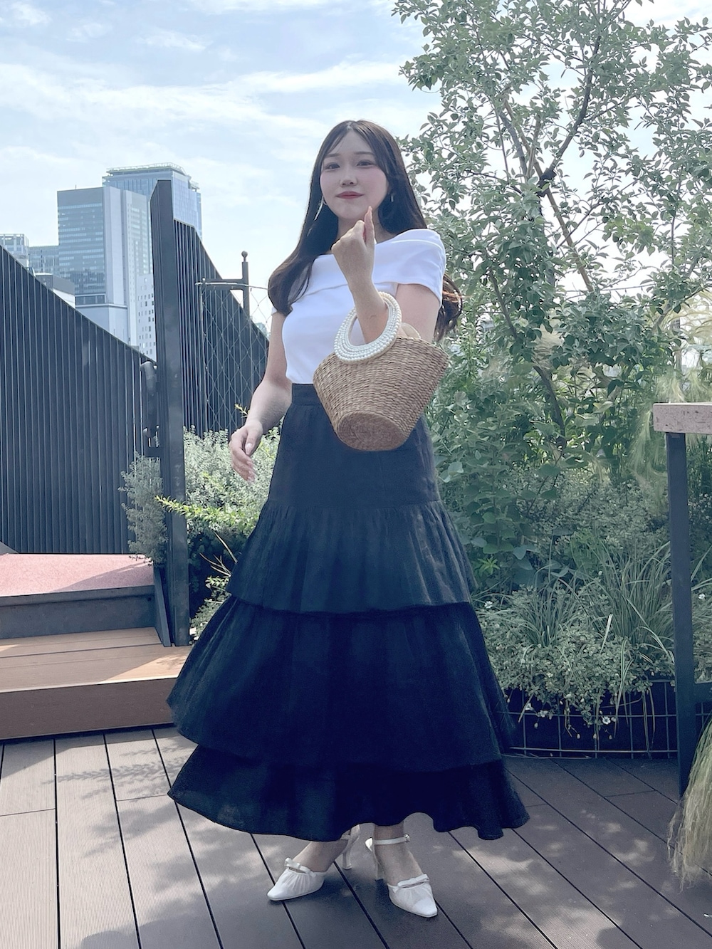 ブラック系のスカート、ベージュ系のかごバッグ、ホワイト系のTシャツ/カットソーを着用したレディースの夏コーディネートの3枚目の写真