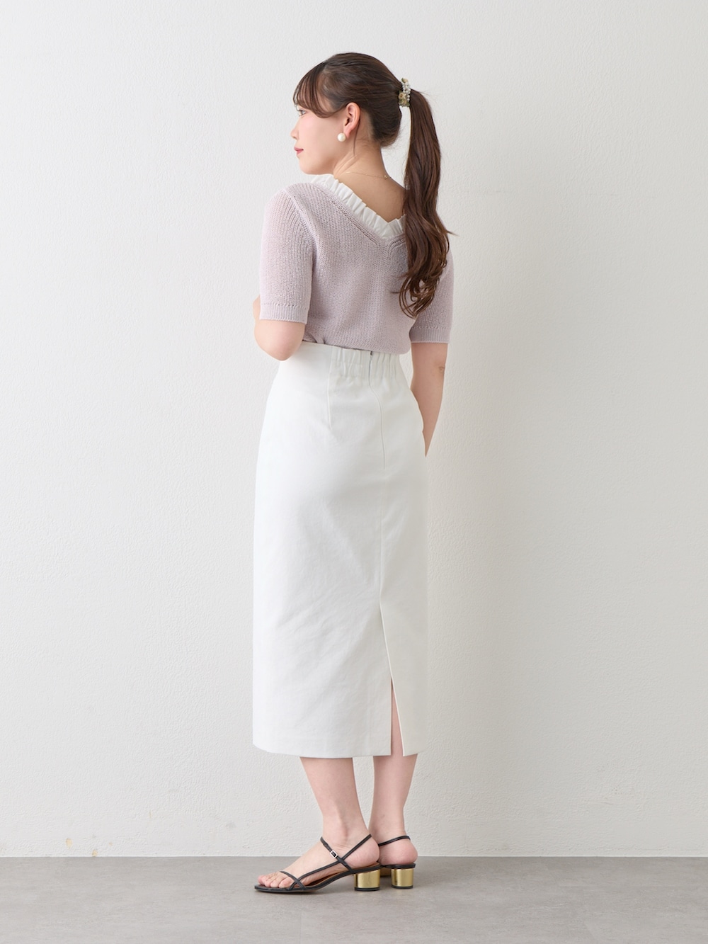 パープル系のニット/セーター、ホワイト系のスカートを着用したレディースの春コーディネートの2枚目の写真
