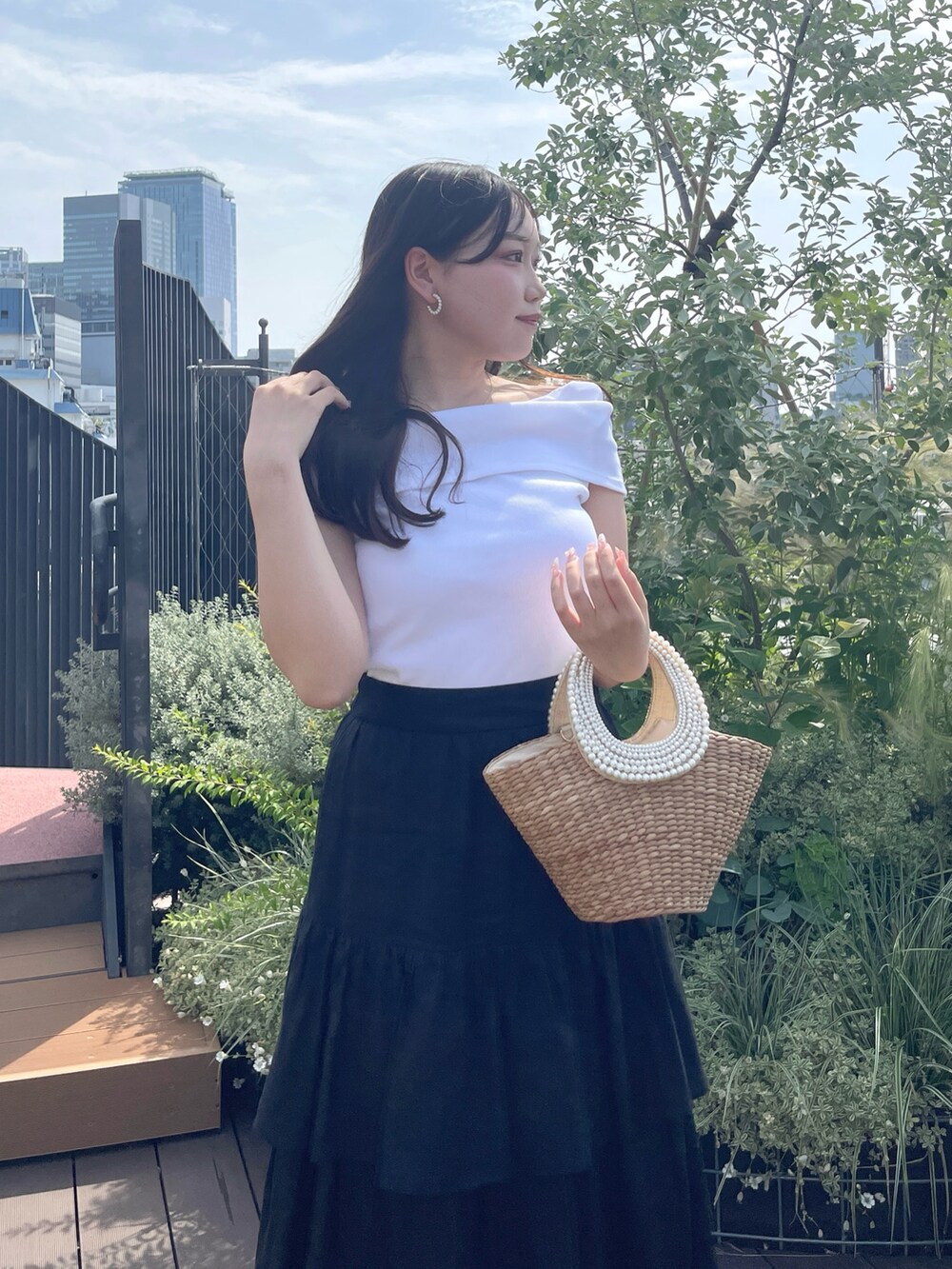 ブラック系のスカート、ベージュ系のかごバッグ、ホワイト系のTシャツ/カットソーを着用したレディースの夏コーディネートの5枚目の写真