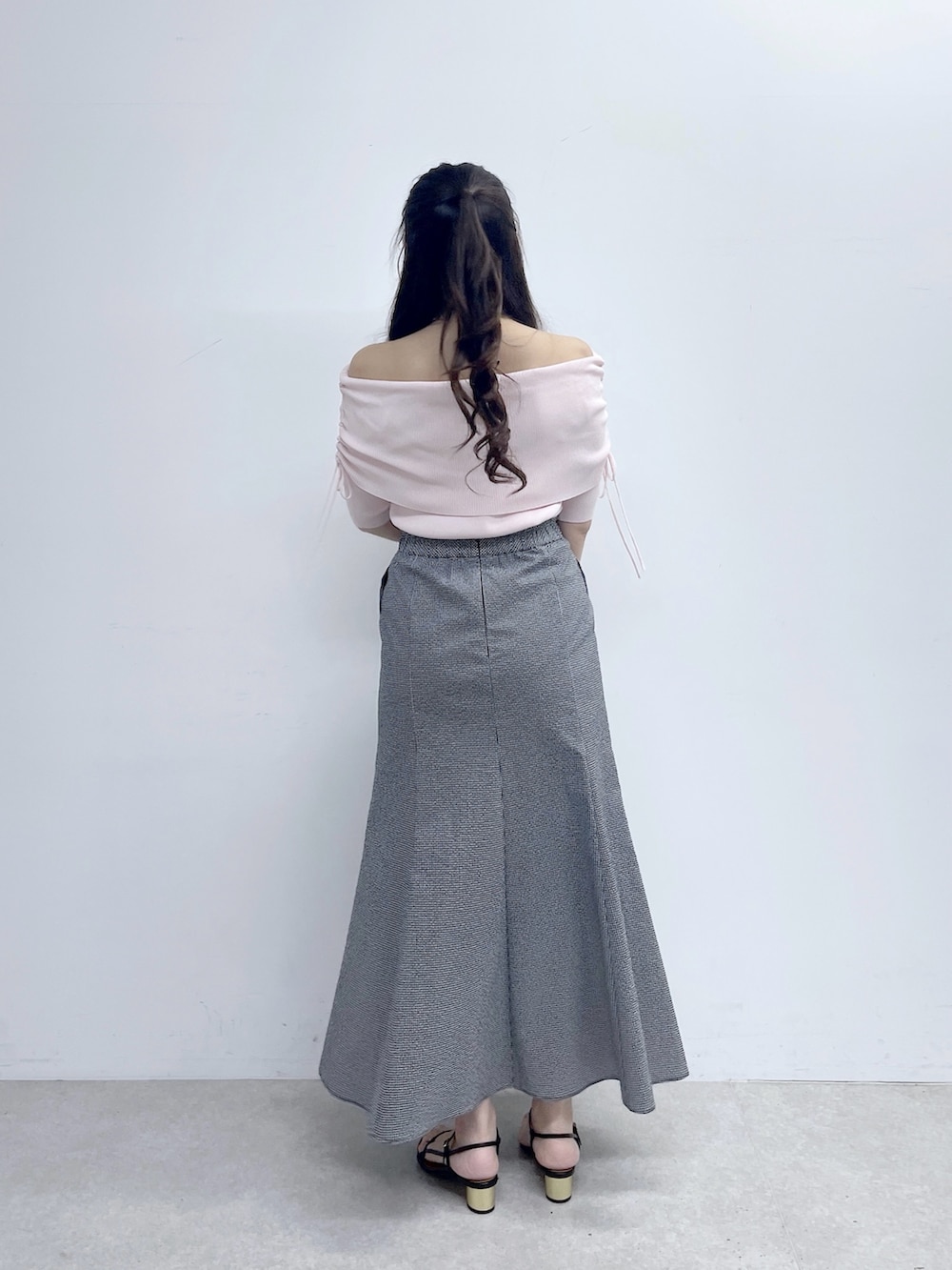 ブラック系のスカート、ピンク系のニット/セーター、ホワイト系のトートバッグを着用したレディースの春コーディネートの4枚目の写真