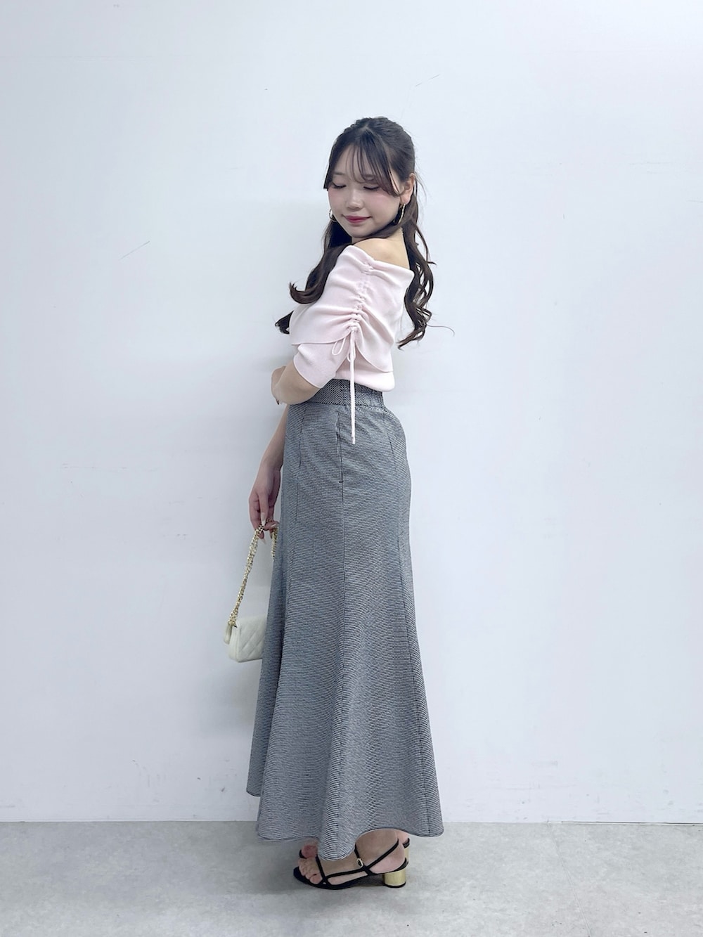 ブラック系のスカート、ピンク系のニット/セーター、ホワイト系のトートバッグを着用したレディースの春コーディネートの3枚目の写真