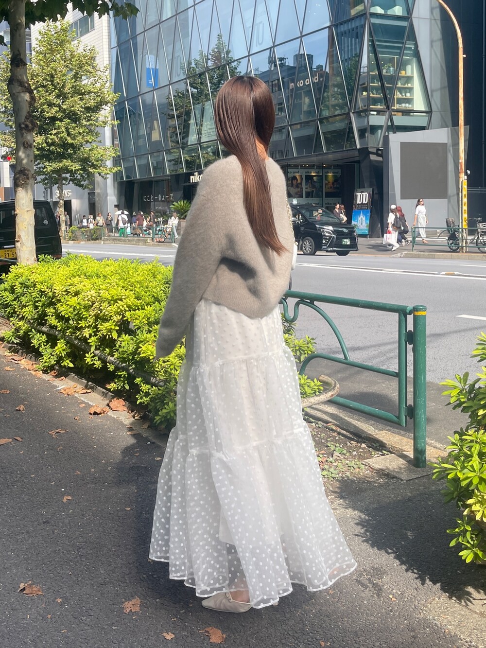 ブラウン系のカーディガン/ボレロ、ホワイト系のスカートを着用したレディースの秋コーディネートの5枚目の写真