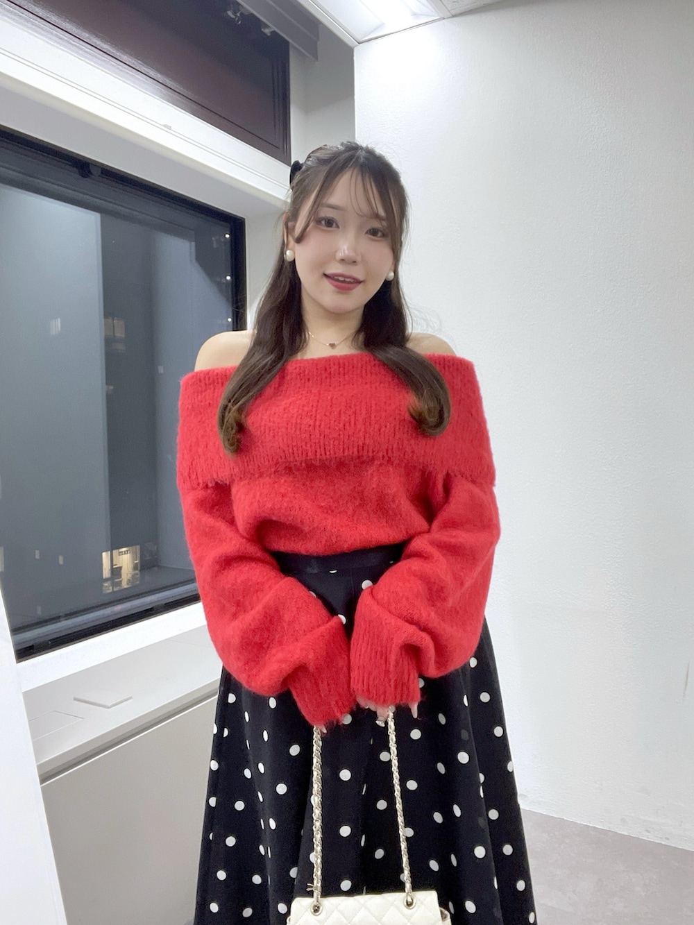 ブルー系のスカート、レッド系のニット/セーター、ゴールド系のネックレスを着用したレディースの秋コーディネートの5枚目の写真