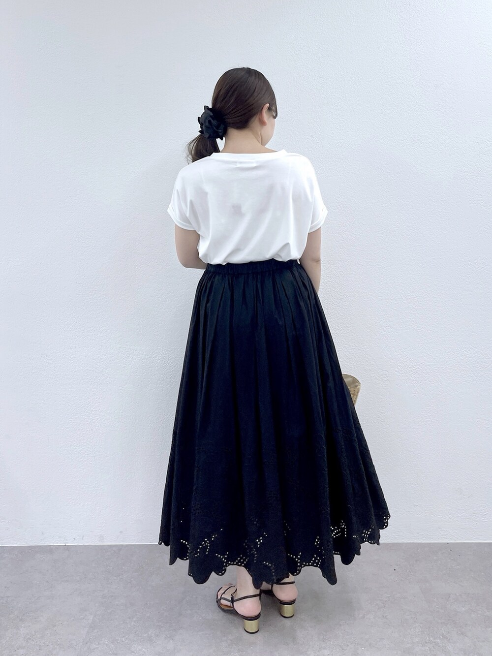 ブラック系のスカート、ベージュ系のかごバッグ、ホワイト系のTシャツ/カットソーを着用したレディースの夏コーディネートの4枚目の写真