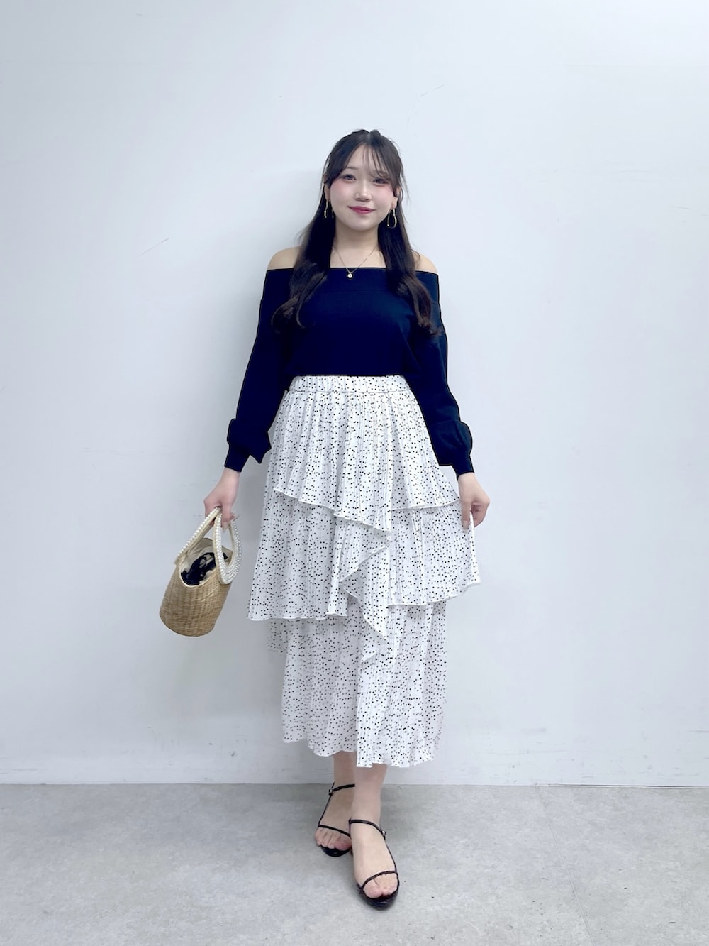 ブルー系のニット/セーター、ホワイト系のスカートを着用したレディースの春コーディネートの2枚目の写真