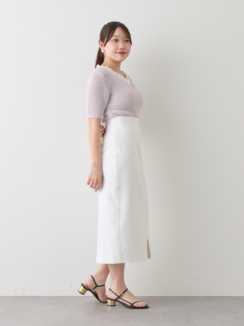 パープル系のニット/セーター、ホワイト系のスカートを着用したレディースの春コーディネートの3枚目の写真