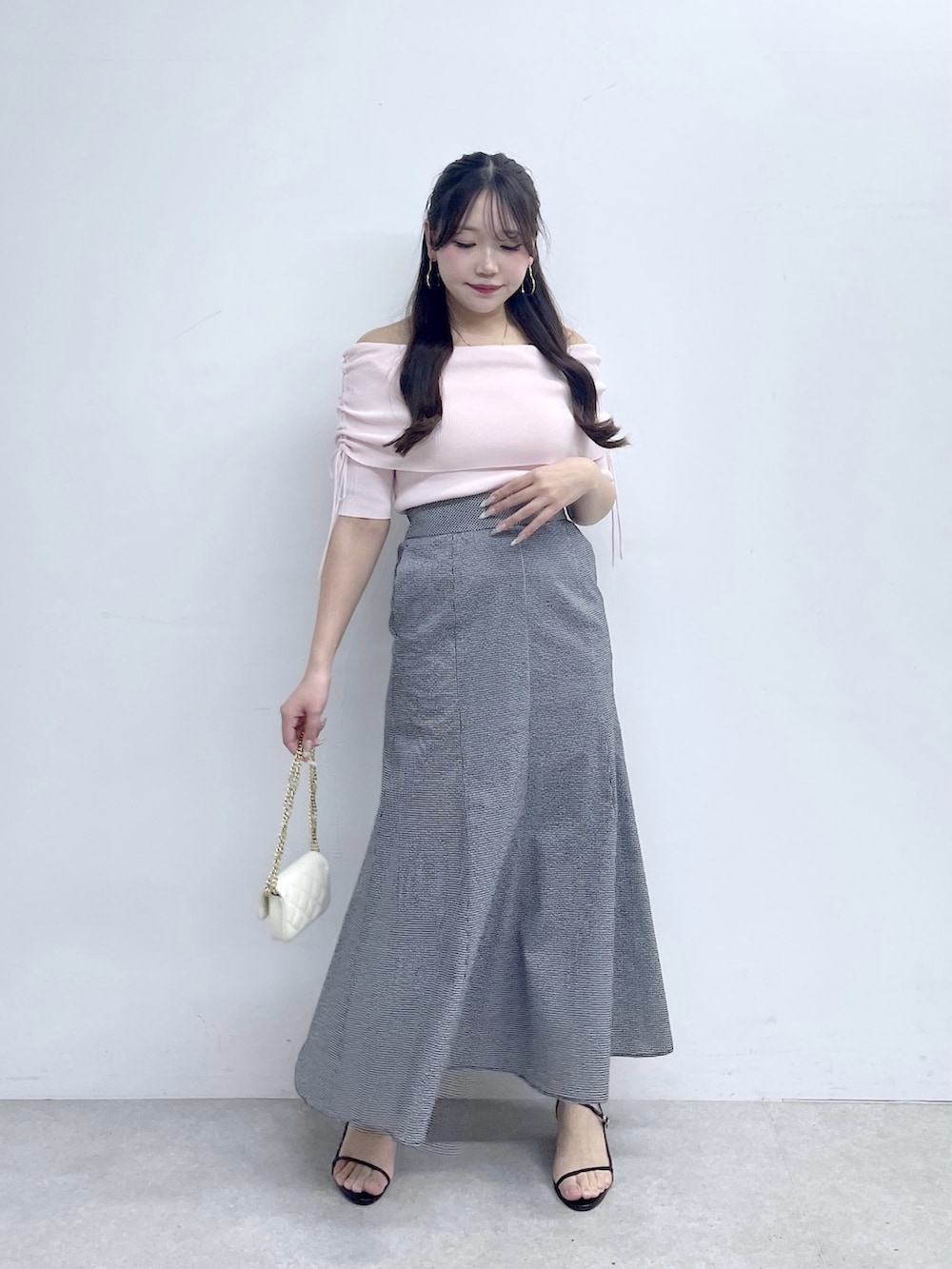 ブラック系のスカート、ピンク系のニット/セーター、ホワイト系のトートバッグを着用したレディースの春コーディネートの2枚目の写真