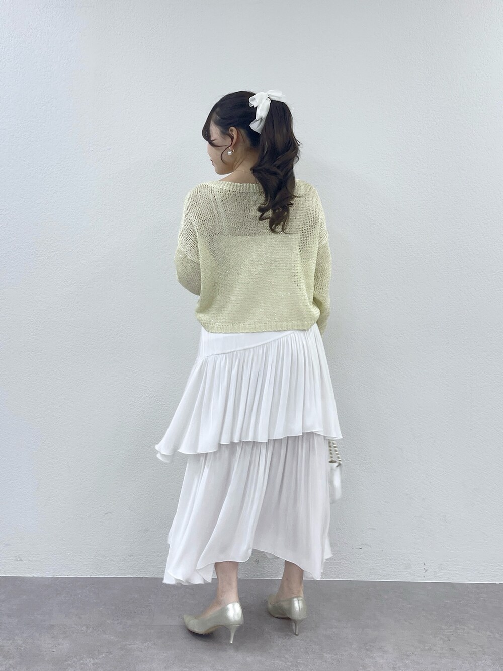 ホワイト系のハンドバッグ、ホワイト系のスカート、イエロー系のニット/セーターを着用したレディースの冬コーディネートの4枚目の写真