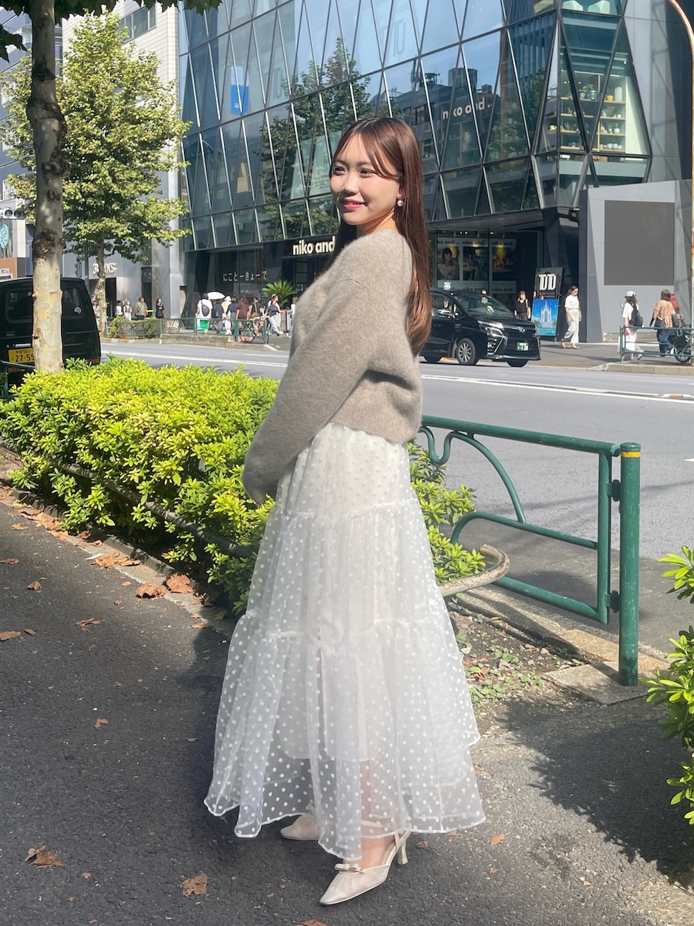 ブラウン系のカーディガン/ボレロ、ホワイト系のスカートを着用したレディースの秋コーディネートの3枚目の写真