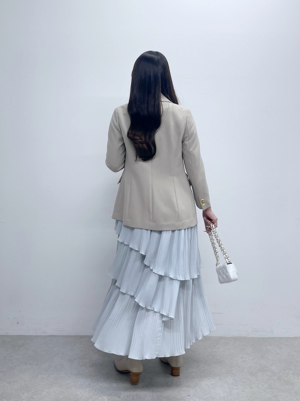 ベージュ系のテーラードジャケット、ホワイト系のニット/セーター、ブルー系のスカートを着用したレディースの春コーディネートの4枚目の写真