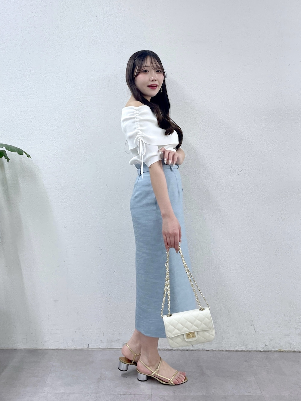 ブルー系のスカート、ホワイト系のニット/セーター、ホワイト系のトートバッグを着用したレディースの春コーディネートの2枚目の写真