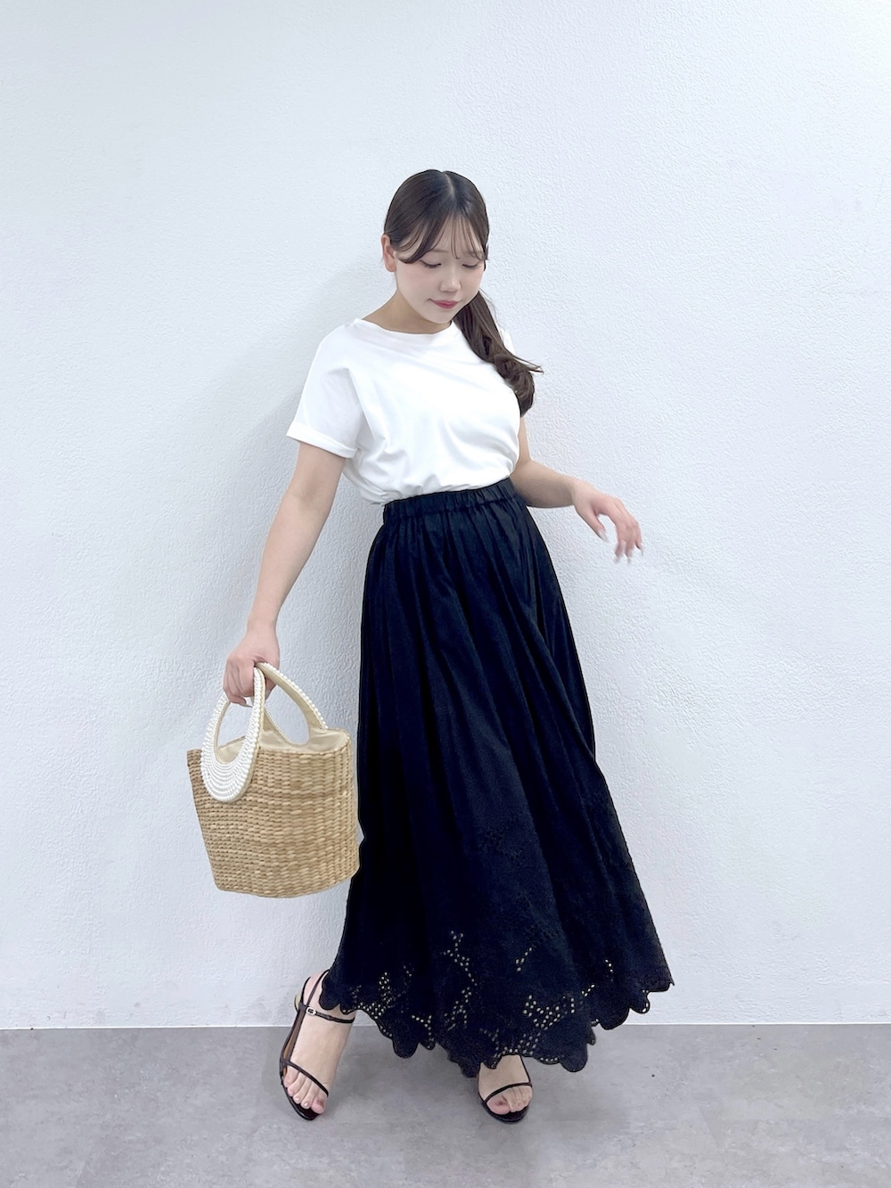 ブラック系のスカート、ベージュ系のかごバッグ、ホワイト系のTシャツ/カットソーを着用したレディースの夏コーディネートの2枚目の写真