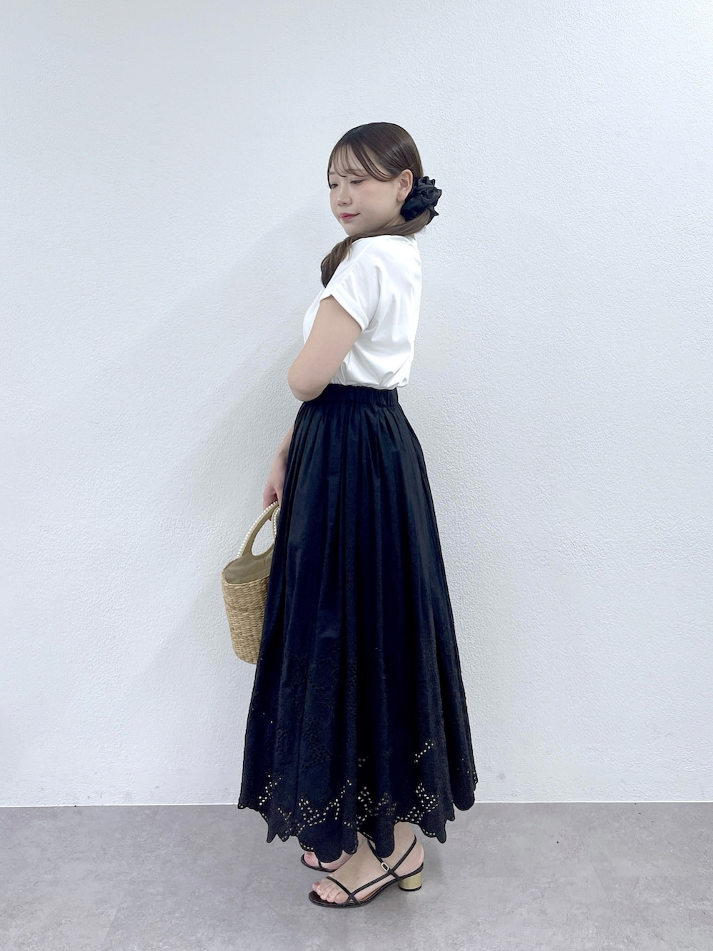 ブラック系のスカート、ベージュ系のかごバッグ、ホワイト系のTシャツ/カットソーを着用したレディースの夏コーディネートの3枚目の写真