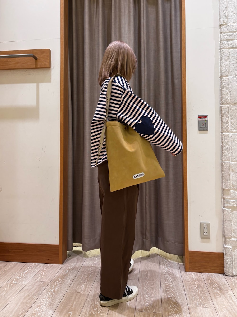 ブラウン系のチノパンツ、イエロー系のトートバッグ、ブルー系のトップスを着用したレディースの冬コーディネートの3枚目の写真