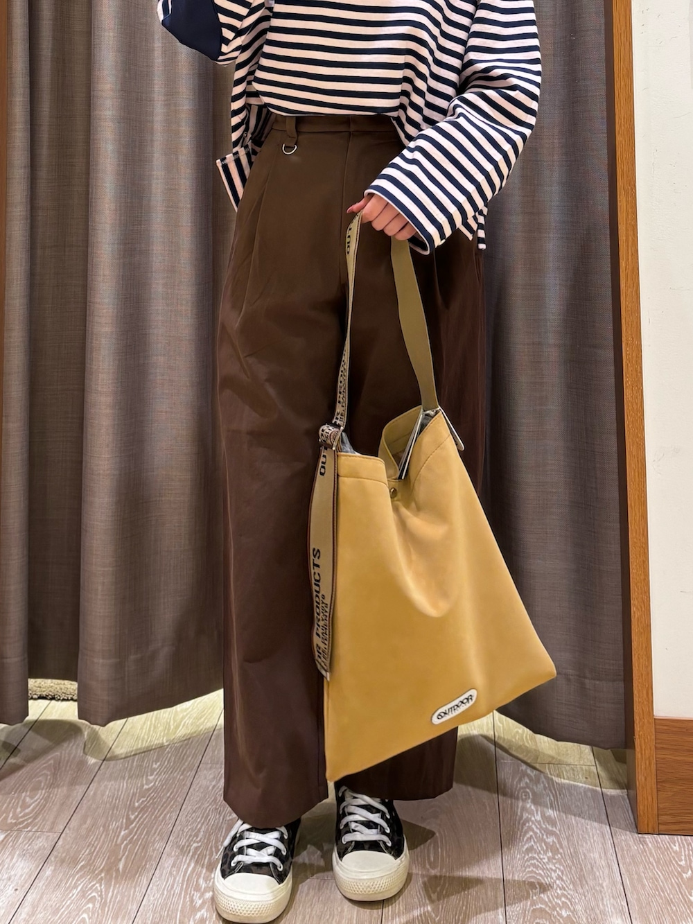 ブラウン系のチノパンツ、イエロー系のトートバッグ、ブルー系のトップスを着用したレディースの冬コーディネートの6枚目の写真