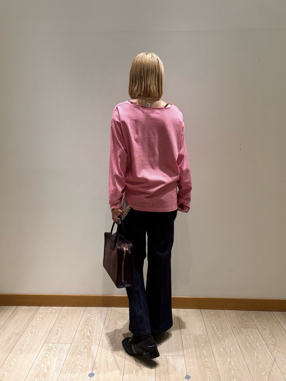 レッド系のTシャツ/カットソー、ブルー系のデニムパンツ、ブラウン系のショルダーバッグを着用したレディースの秋コーディネートの5枚目の写真