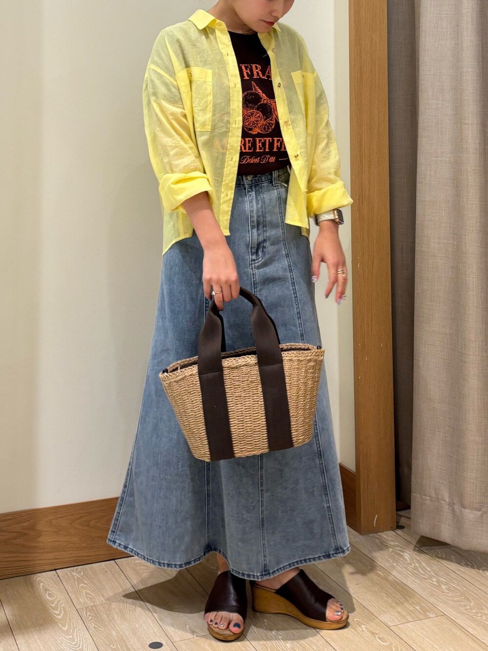 ブラウン系のTシャツ/カットソー、イエロー系のシャツ/ブラウス、ブルー系のデニムスカートを着用したレディースの夏コーディネートの3枚目の写真