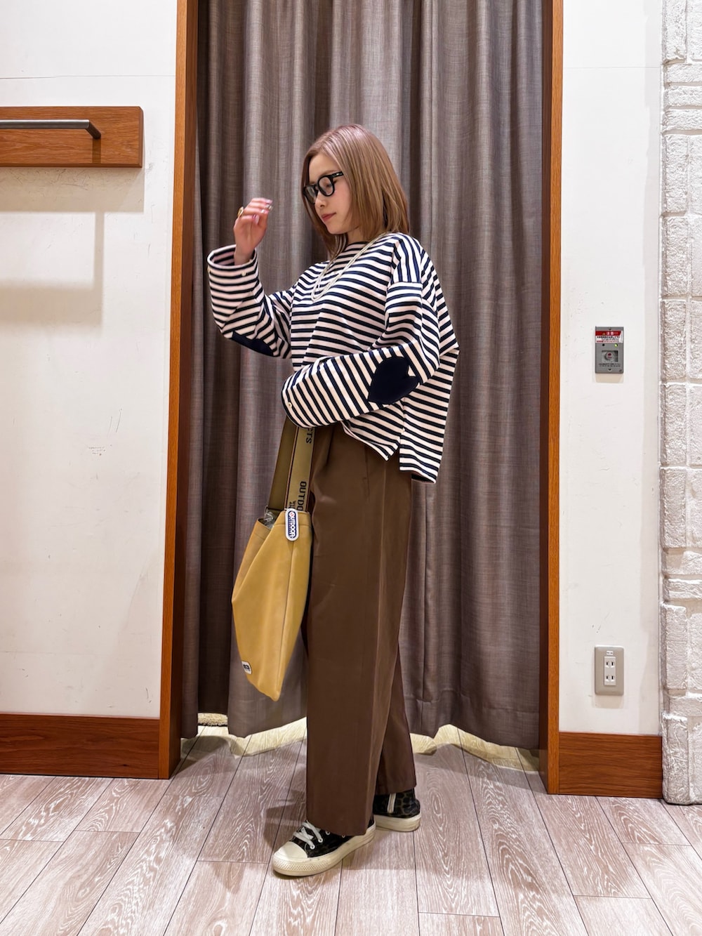 ブラウン系のチノパンツ、イエロー系のトートバッグ、ブルー系のトップスを着用したレディースの冬コーディネートの2枚目の写真