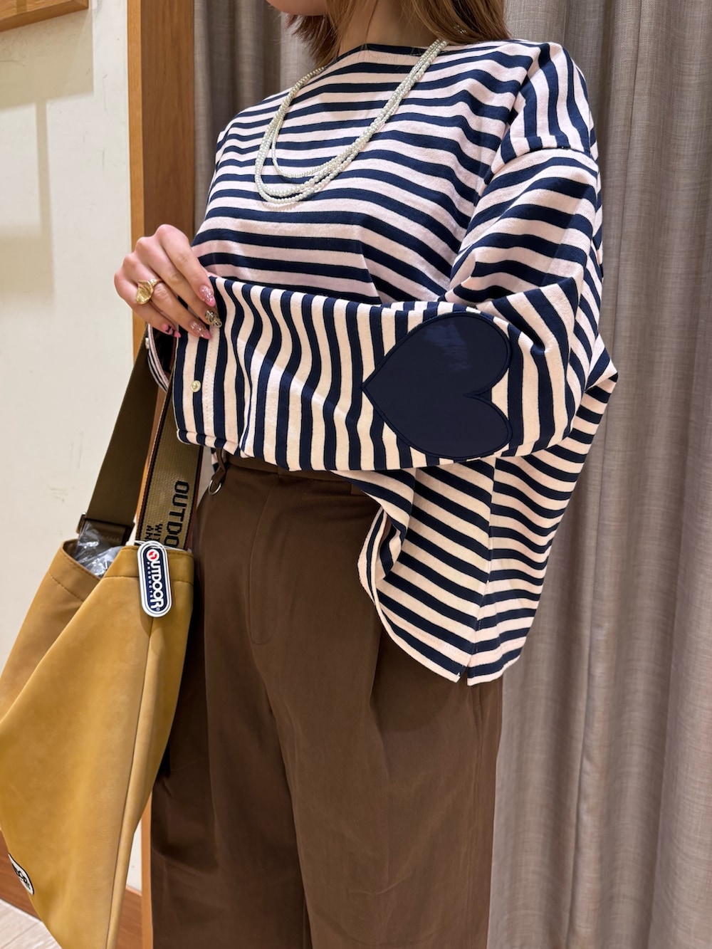 ブラウン系のチノパンツ、イエロー系のトートバッグ、ブルー系のトップスを着用したレディースの冬コーディネートの5枚目の写真