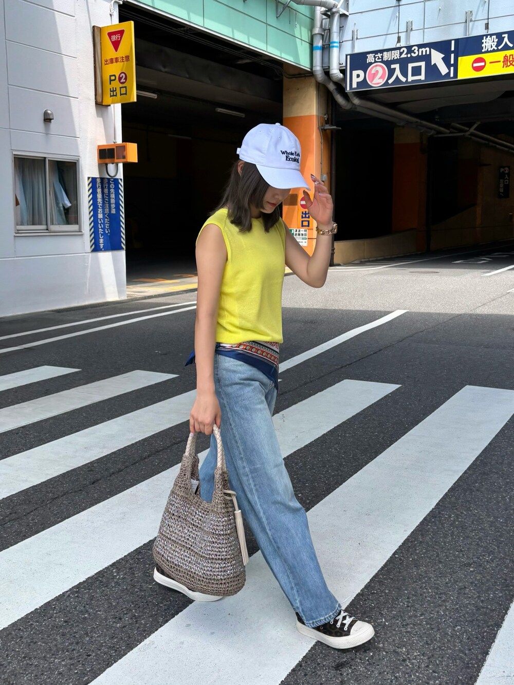 イエロー系のタンクトップ、ブルー系のデニムパンツ、ベージュ系のかごバッグを着用したレディースの夏コーディネートの4枚目の写真