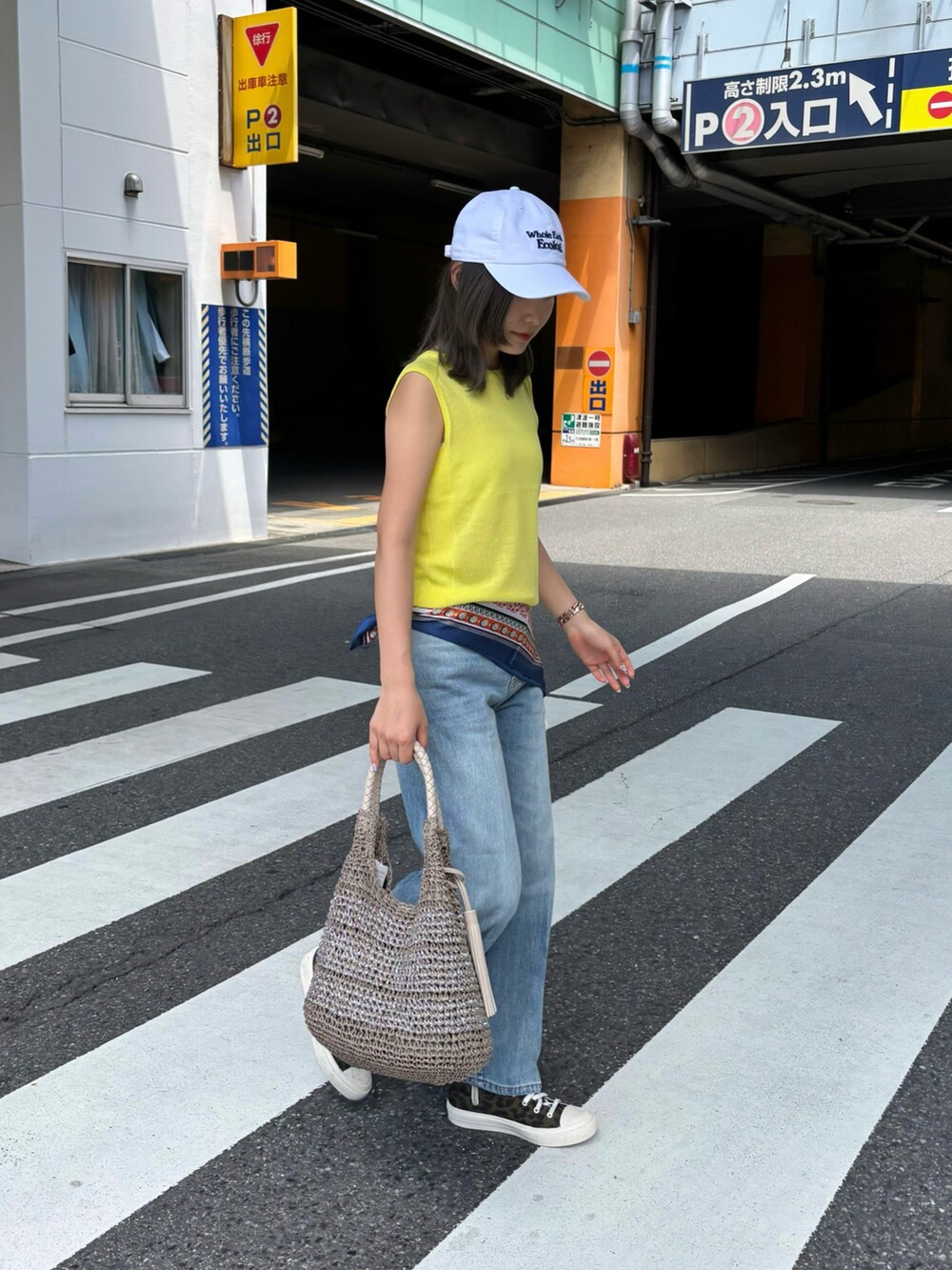 イエロー系のタンクトップ、ブルー系のデニムパンツ、ベージュ系のかごバッグを着用したレディースの夏コーディネートの5枚目の写真