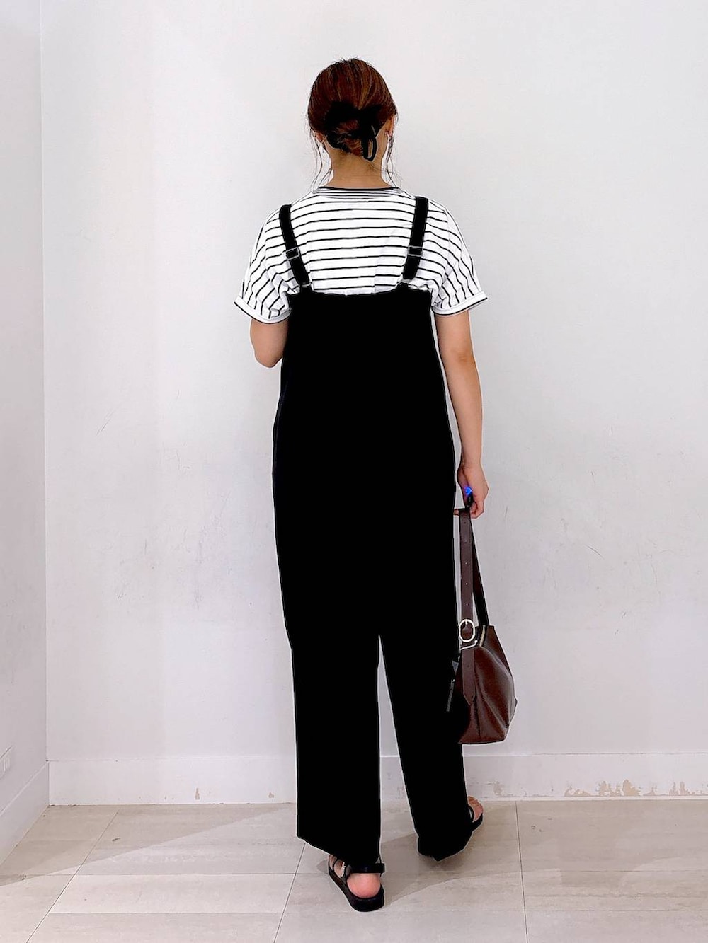 ブラウン系のショルダーバッグ、ブラック系のつなぎ/オールインワン、ホワイト系のTシャツ/カットソーを着用したレディースの夏コーディネートの3枚目の写真