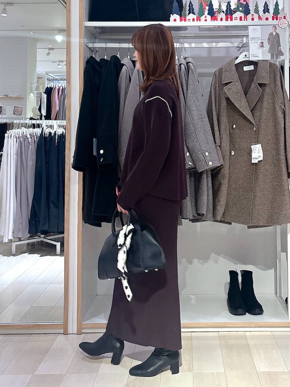 ブラック系のショルダーバッグ、ブラウン系のワンピース、ブラック系のブーツを着用したレディースの冬コーディネートの2枚目の写真