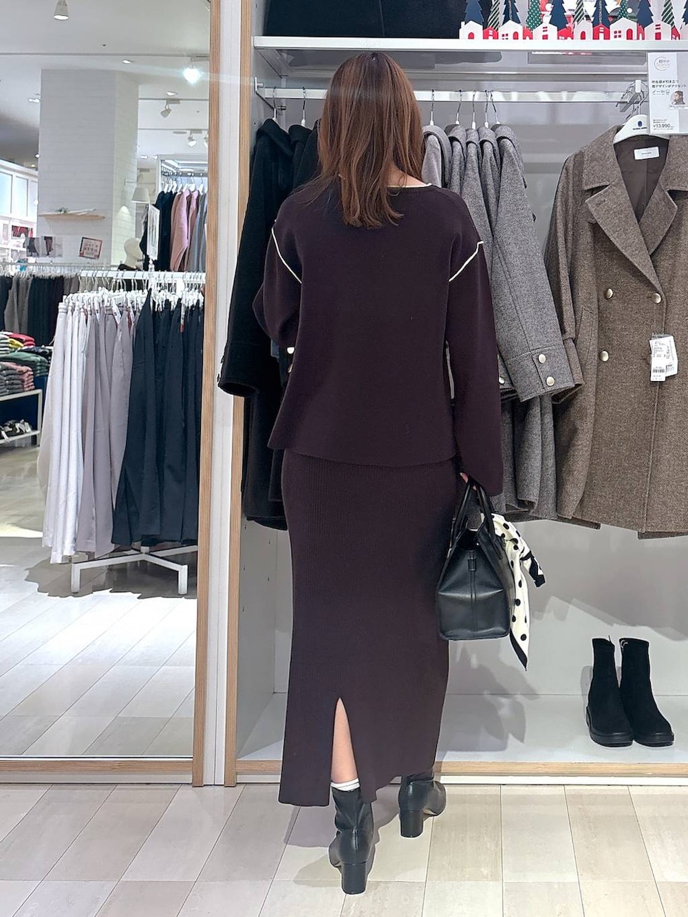 ブラック系のショルダーバッグ、ブラウン系のワンピース、ブラック系のブーツを着用したレディースの冬コーディネートの3枚目の写真