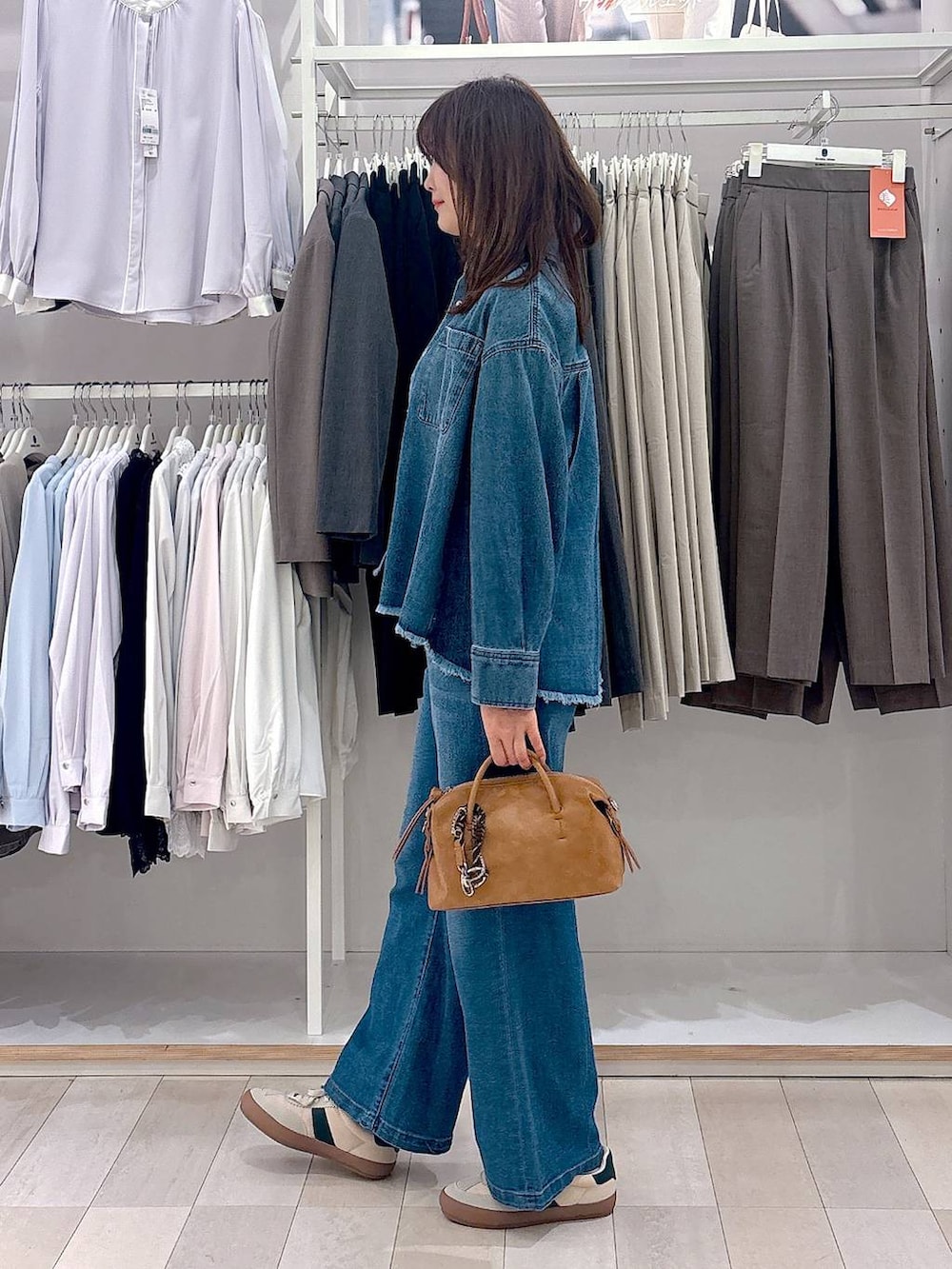 ベージュ系のスニーカー、ブルー系のシャツ/ブラウス、ブルー系のデニムパンツを着用したレディースの春コーディネートの2枚目の写真