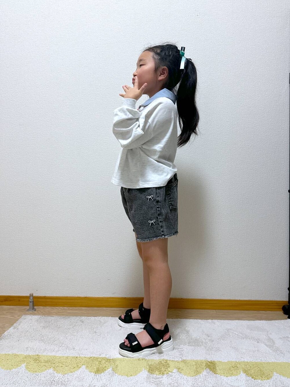 ブラック系のデニムパンツ、ブラック系のサンダル、グレー系のTシャツ/カットソーを着用したキッズの秋コーディネートの2枚目の写真