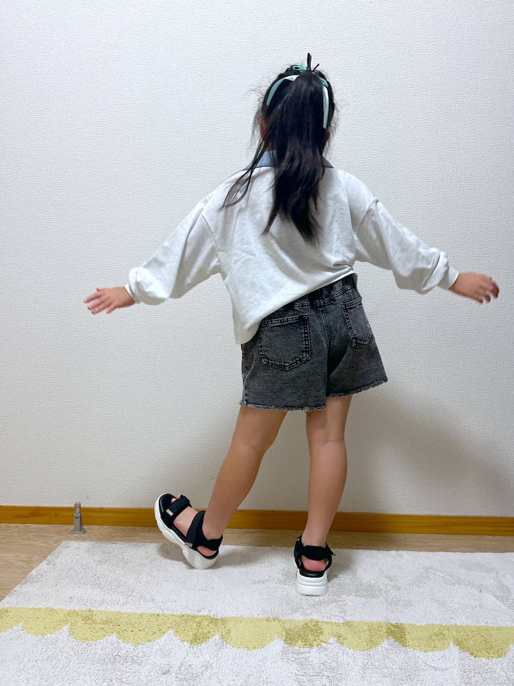 ブラック系のデニムパンツ、ブラック系のサンダル、グレー系のTシャツ/カットソーを着用したキッズの秋コーディネートの3枚目の写真