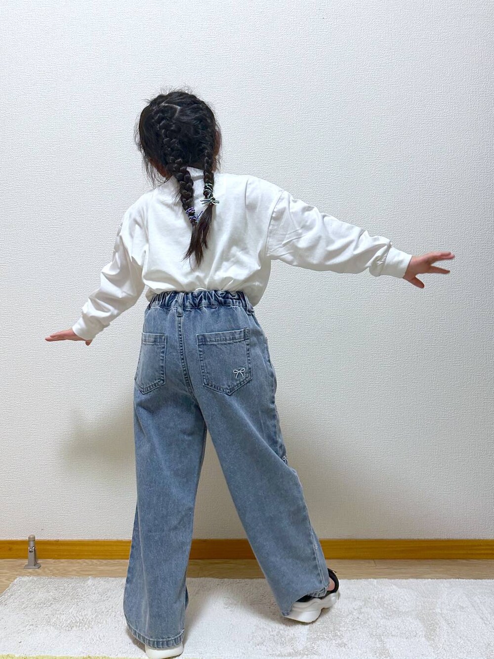 ブルー系のデニムパンツ、ブラック系のサンダル、ホワイト系のTシャツ/カットソーを着用したキッズの秋コーディネートの3枚目の写真