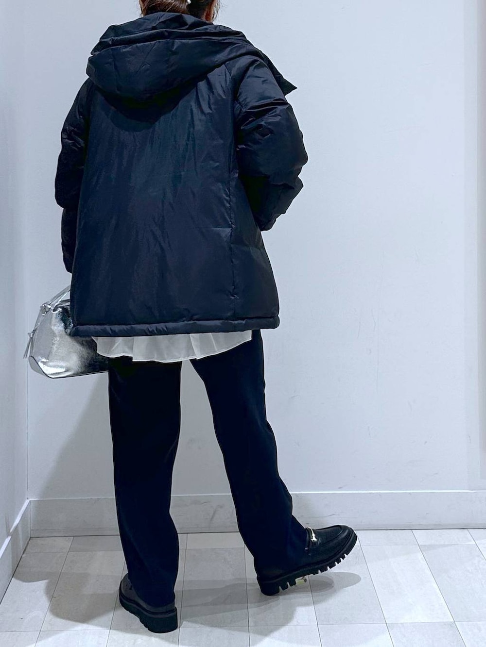 シルバー系のショルダーバッグ、ブルー系のダウンジャケット/コート、ブラック系のローファーを着用したレディースの秋コーディネートの3枚目の写真