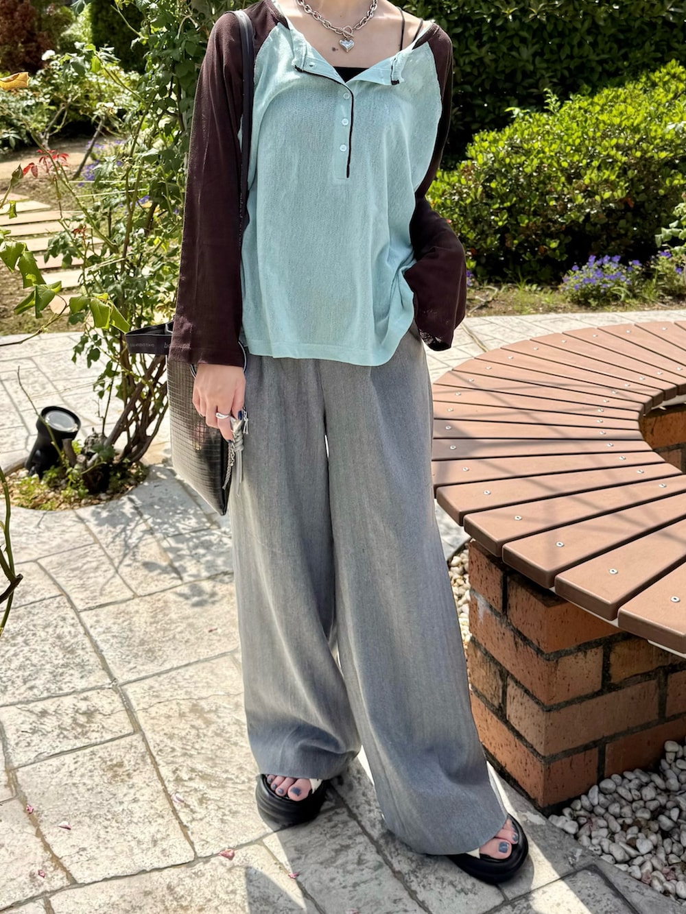 グリーン系のTシャツ/カットソー、グレー系のスラックス、ホワイト系のサンダルを着用したレディースの夏コーディネートの3枚目の写真