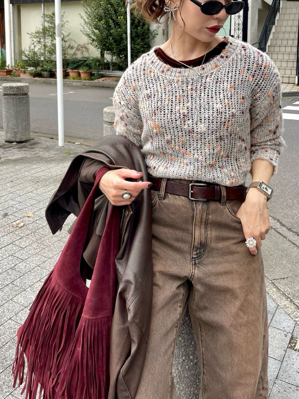ベージュ系のニット/セーター、ブラウン系のデニムパンツ、レッド系のトートバッグを着用したレディースの冬コーディネートの3枚目の写真