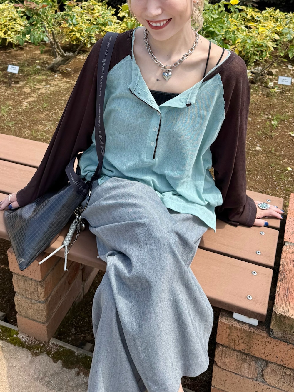 グリーン系のTシャツ/カットソー、グレー系のスラックス、ホワイト系のサンダルを着用したレディースの夏コーディネートの4枚目の写真