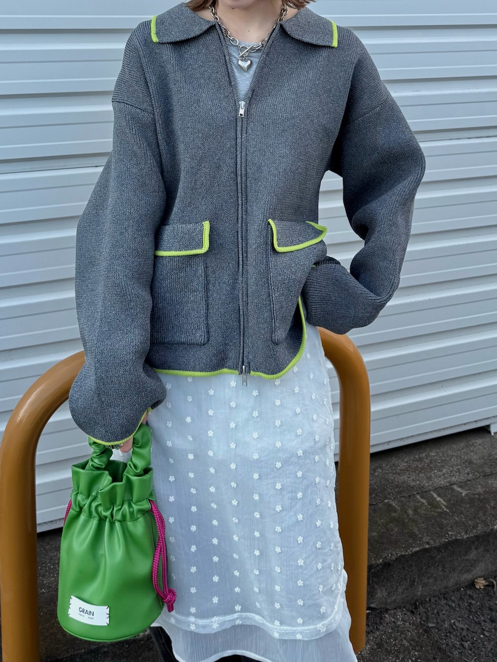 グレー系のカーディガン/ボレロ、ホワイト系のワンピース、グリーン系のハンドバッグを着用したレディースの秋コーディネートの3枚目の写真