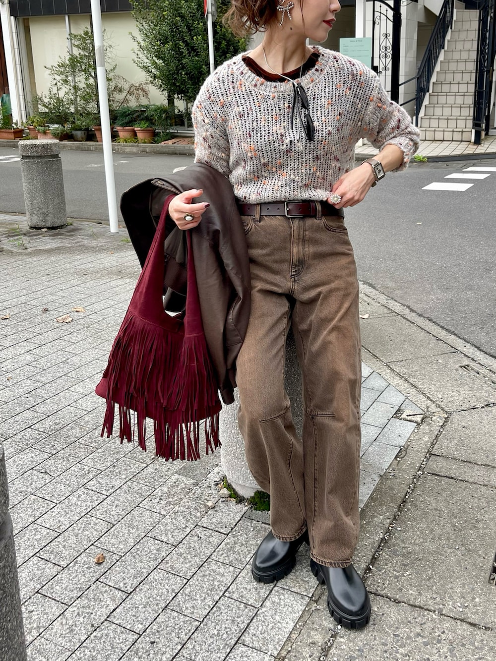 ベージュ系のニット/セーター、ブラウン系のデニムパンツ、レッド系のトートバッグを着用したレディースの冬コーディネートの2枚目の写真