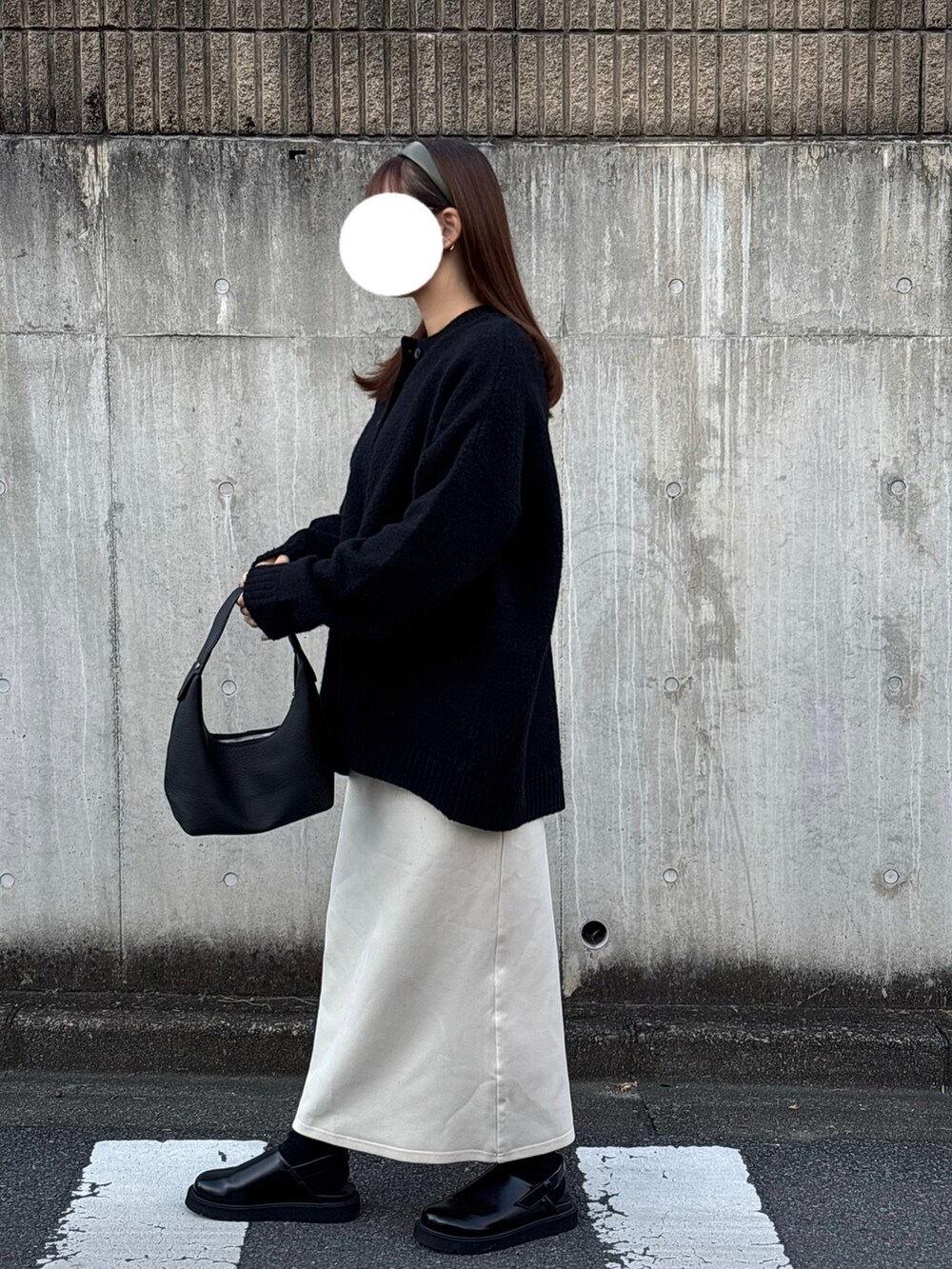 ブラック系のシューズ、ホワイト系のスカート、ブラック系のニット/セーターを着用したレディースの冬コーディネートの2枚目の写真