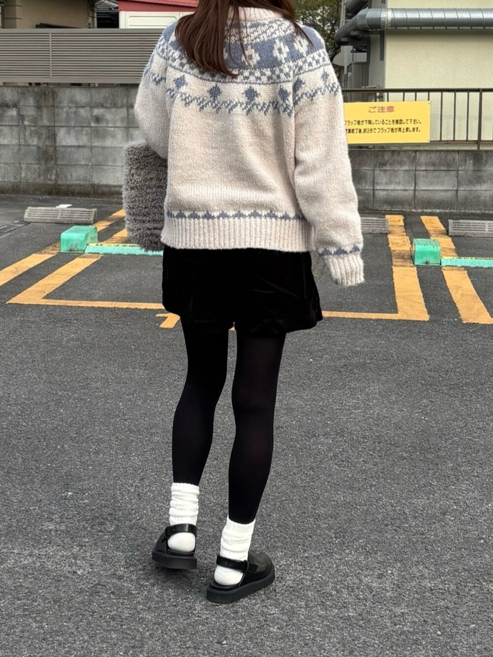 ホワイト系のニット/セーター、ブラック系のスカート、ブラック系のスリッポンを着用したレディースの冬コーディネートの2枚目の写真