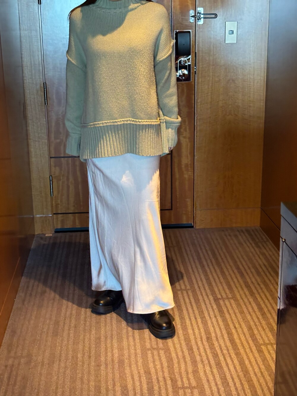 グリーン系のニット/セーター、ブラック系のショルダーバッグ、ブラック系のブーツを着用したレディースの冬コーディネートの3枚目の写真