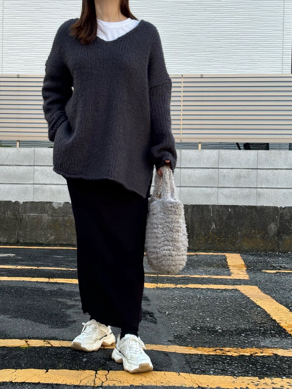 ブラック系のスカート、グレー系のニット/セーターを着用したレディースの秋コーディネートの2枚目の写真