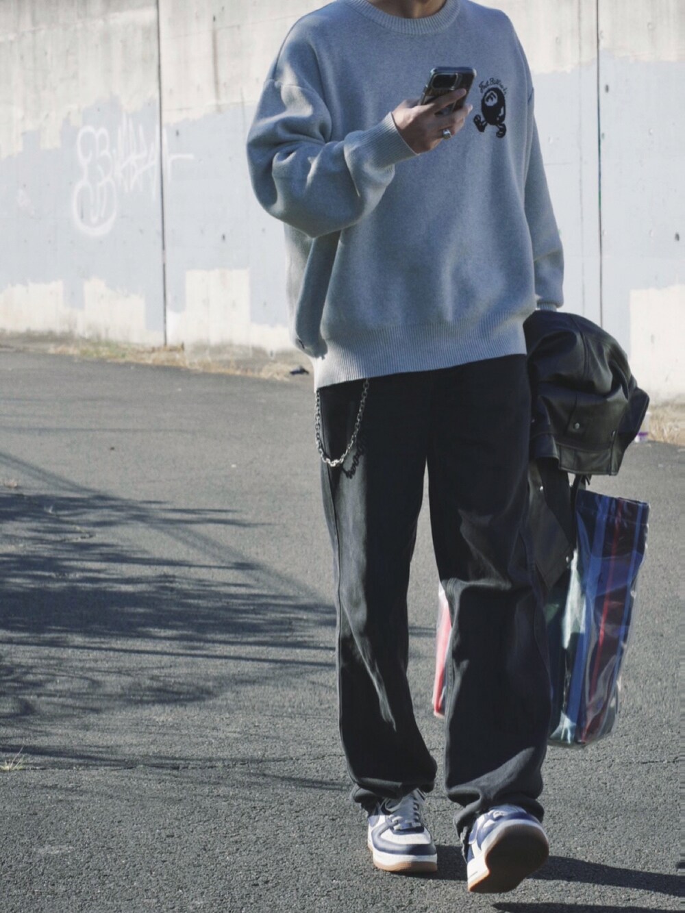 ブラック系のデニムパンツ、グレー系のニット/セーター、ブルー系のスニーカーを着用したメンズの冬コーディネートの3枚目の写真