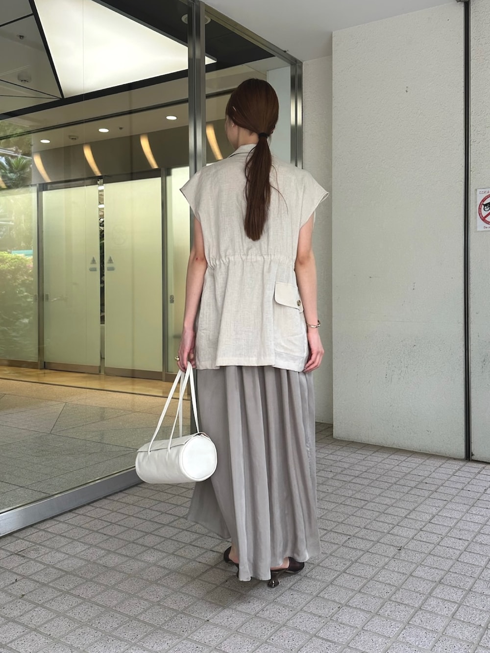 ベージュ系のワンピース、ベージュ系のベスト、ブラウン系のサンダルを着用したレディースの夏コーディネートの4枚目の写真