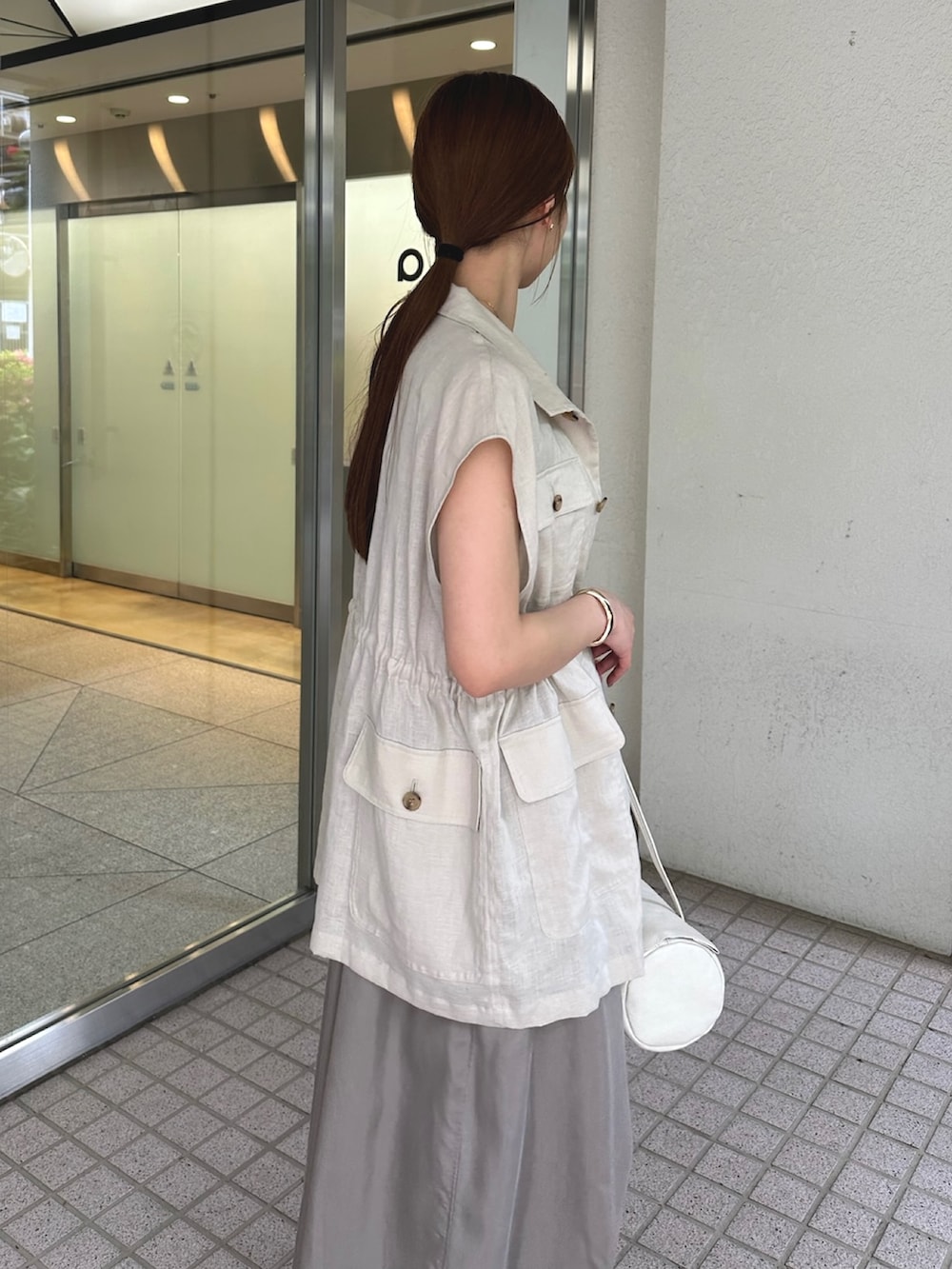 ベージュ系のワンピース、ベージュ系のベスト、ブラウン系のサンダルを着用したレディースの夏コーディネートの6枚目の写真