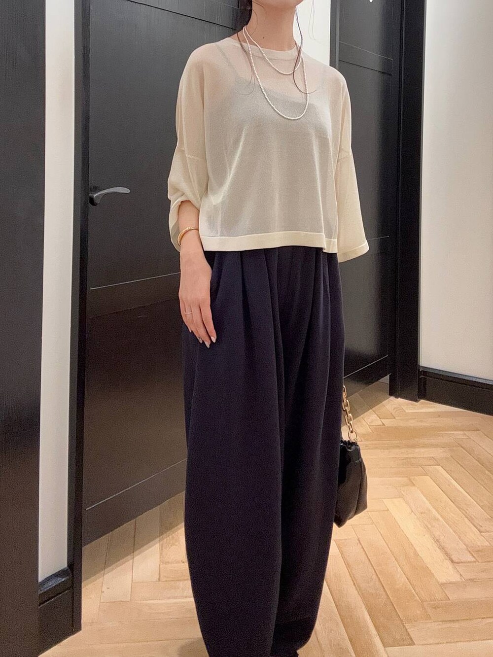 ブルー系のスウェットパンツ、ホワイト系のニット/セーター、ブラウン系のパンプスを着用したレディースの夏コーディネートの4枚目の写真