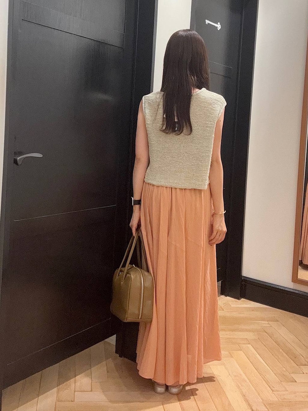 ブラウン系のボストンバッグ、シルバー系のパンプス、ホワイト系のニット/セーターを着用したレディースの夏コーディネートの3枚目の写真