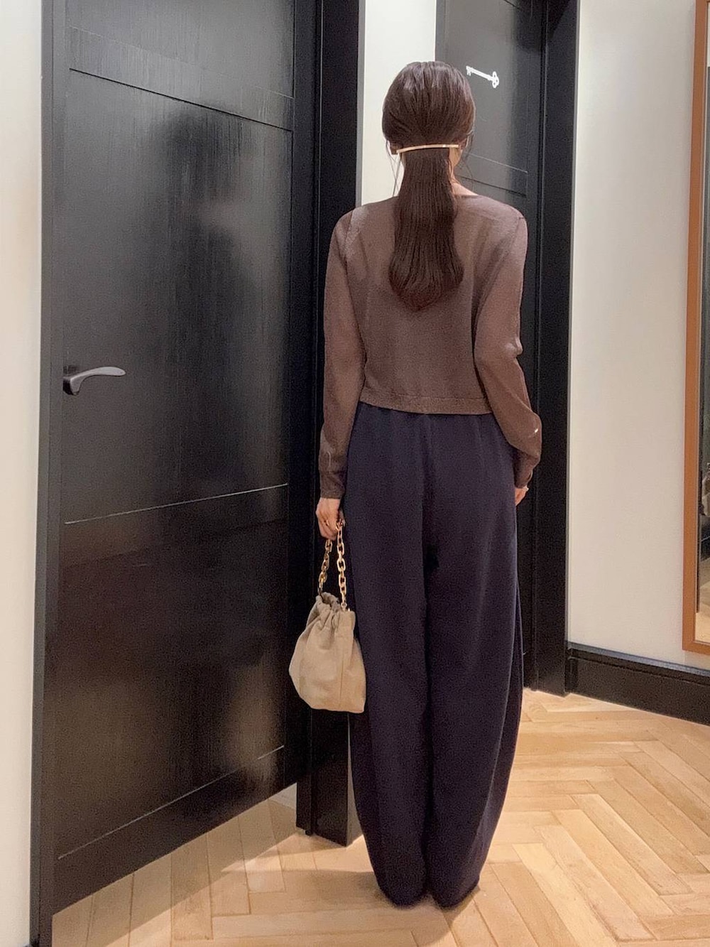 ブルー系のスウェットパンツ、ブラウン系のパンプス、ベージュ系のショルダーバッグを着用したレディースの夏コーディネートの3枚目の写真