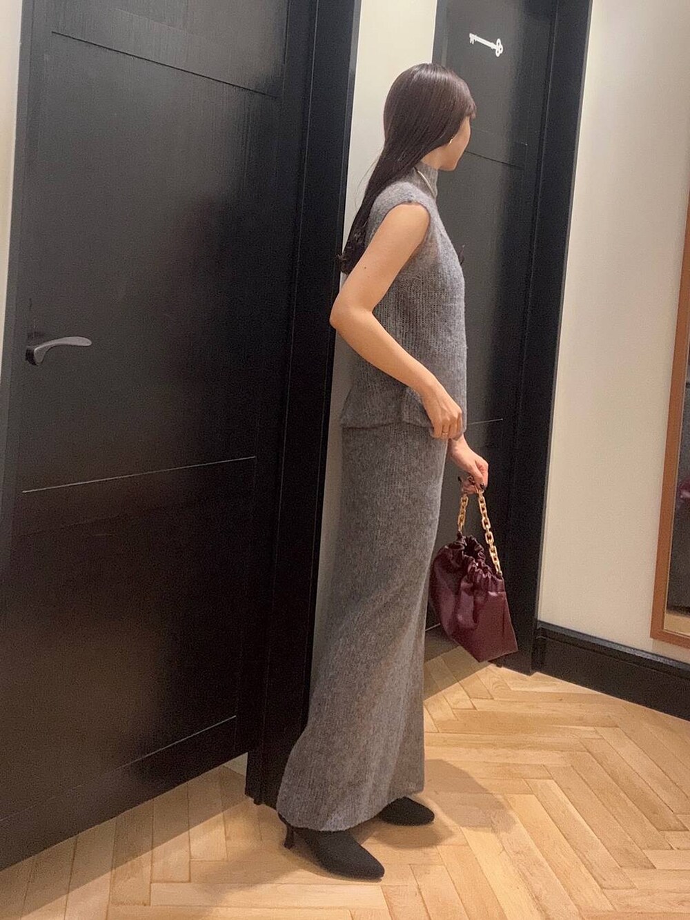 グレー系のワンピース、レッド系のショルダーバッグ、ブラック系のブーツを着用したレディースの秋コーディネートの2枚目の写真