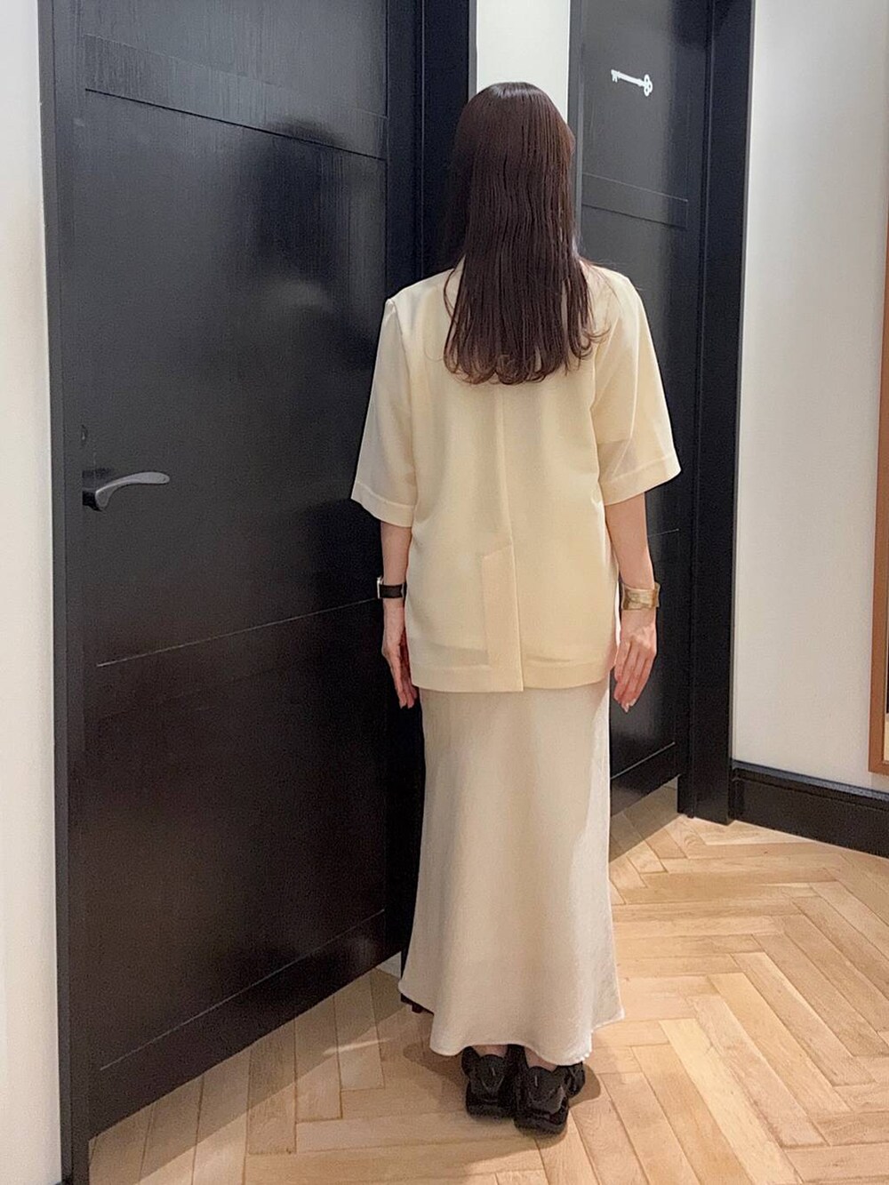 ホワイト系のスカート、ホワイト系のTシャツ/カットソー、ブラック系のスニーカーを着用したレディースの夏コーディネートの3枚目の写真